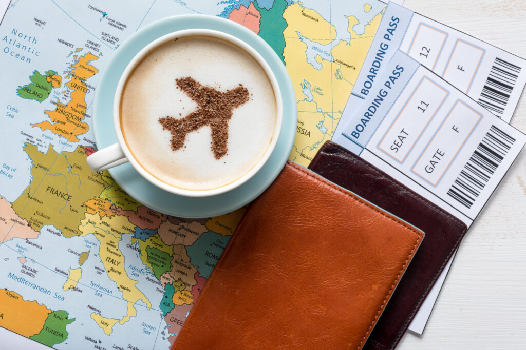 Kaffee in Tasse und Reisepass liegend auf einer Landkarte